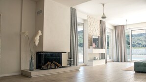 Un salón amplio con chimenea, ventanas grandes y vistas al exterior.