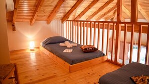 Ein gemütliches Schlafzimmer mit Holzboden und -decke, einem Bett mit Kissen und einem Nachttisch mit Lampe.