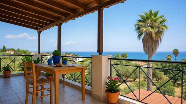 Eine überdachte Terrasse mit Holztisch und -stühlen, Blumentöpfen und Blick auf Meer und Palmen.