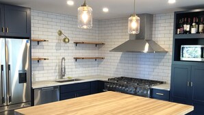 A modern kitchen with a central island, stainless steel appliances, and a built-in oven.