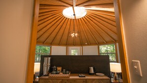 A kitchen with a wooden ceiling, a central light fixture, and a window with a view of greenery. - Relax in your own secluded Yurt Cabin nestled into a 200+ acre Property! (Bastrop)