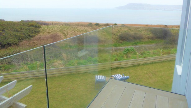 A balcony with a view of the sea and grassy landscape. - Blue Horizons with uninterrupted Panoramic sea views 2 mins walk from beach (Weymouth)