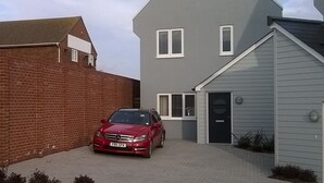 A two-story residential building with a red car parked in the driveway. - Blue Horizons with uninterrupted Panoramic sea views 2 mins walk from beach (Weymouth)