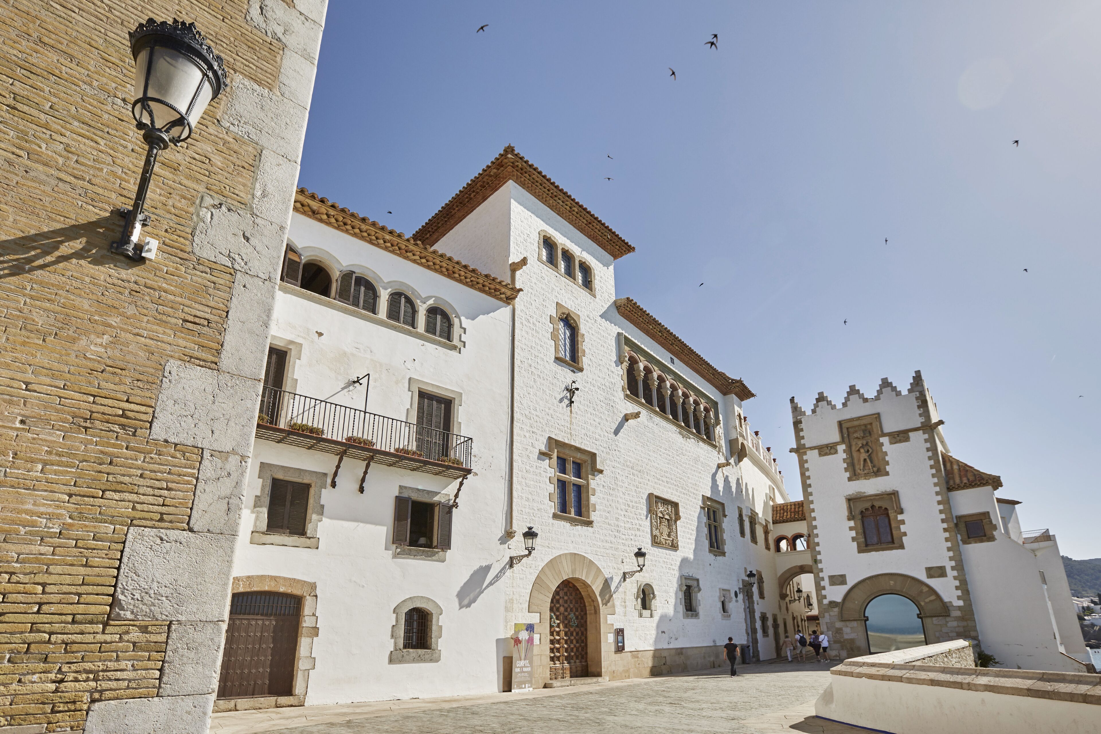 Un edificio histórico con fachada blanca, múltiples arcos y una torre con reloj.