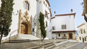 Un bâtiment historique doté d’une entrée imposante, d’une cour pavée et d’un toit traditionnel recouvert de tuiles.