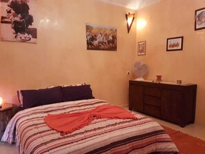 A bedroom with a bed, a nightstand, a dresser, and wall-mounted artwork. - Appart-Maison-Zaitouna (Marrakech)