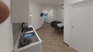 A modern kitchen with a sink, a countertop, and a wall-mounted TV. - Dormire a Napoli Centro Holiday House (Naples)
