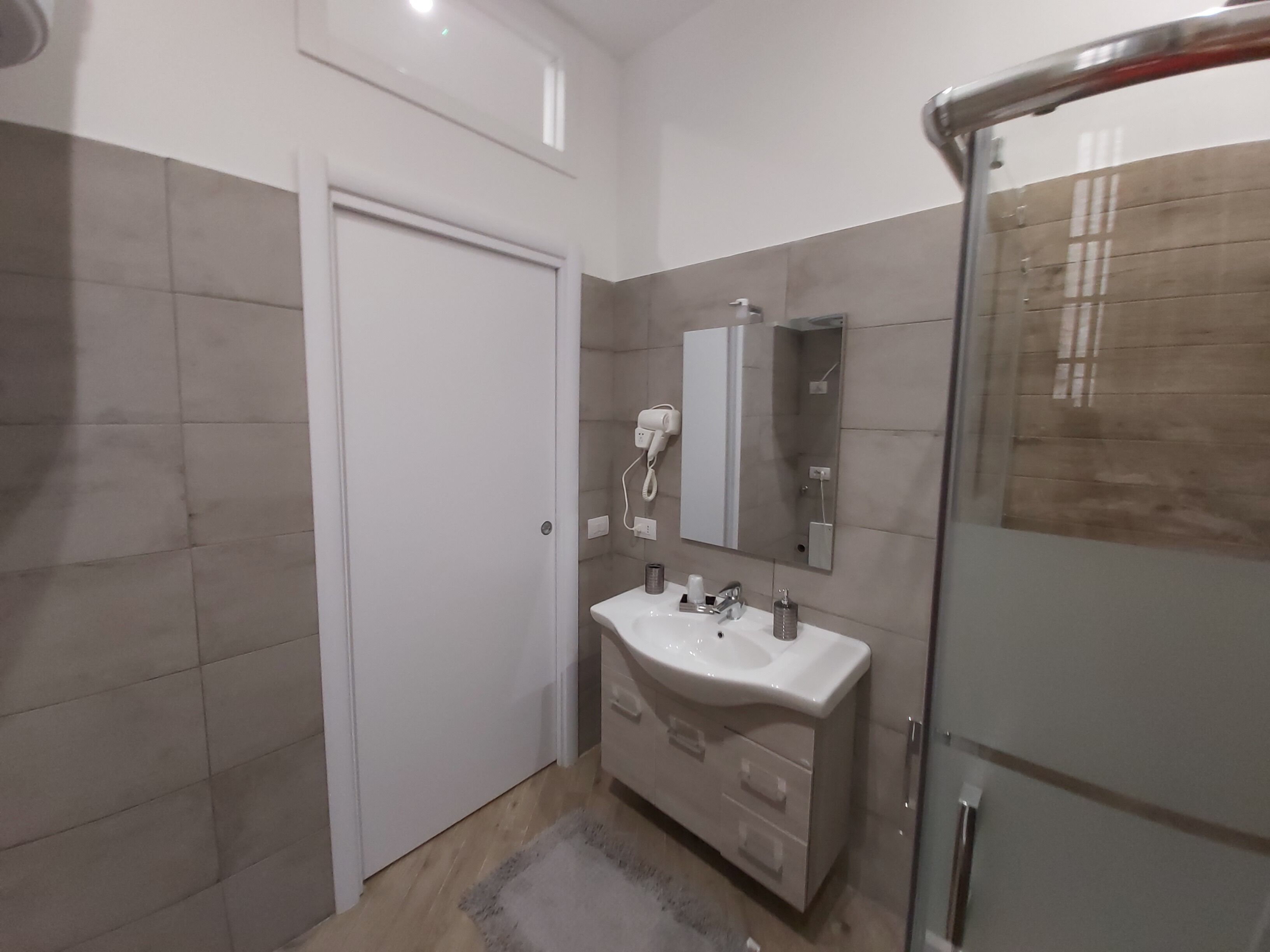 A bathroom with a white sink, mirror, and shower.