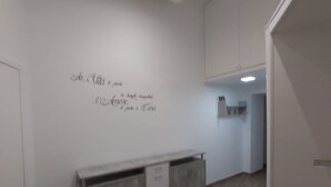 A spacious room with a wooden floor, a white wall with decorative text, and a grey cabinet. - Dormire a Napoli Centro Holiday House (Naples)