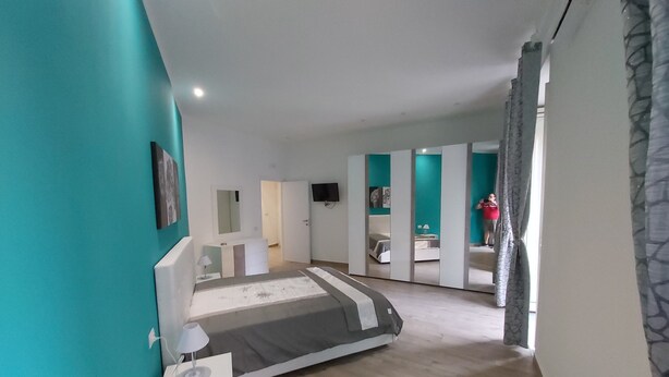 A bedroom with a bed, a bedside table, a mirror, and a wardrobe. - Dormire a Napoli Centro Holiday House (Naples)