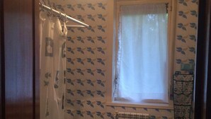 A small bathroom with a toilet, bidet, and a window with a curtain.