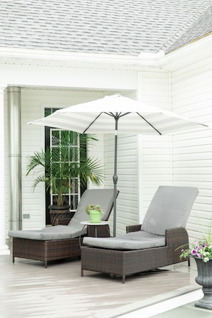 A covered outdoor seating area with wicker furniture and a large umbrella. - Southern luxury home (State College)