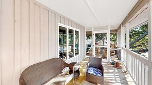 Ein überdachter Balkon mit Korbmöbeln und Blick auf den Garten.