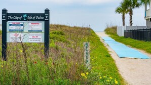 Ein Strandweg mit einem Schild, das 'The City of Isle of Palm' und 'Strand' sowie Notrufnummern zeigt.