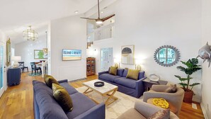 Ein geräumiges Wohnzimmer mit hohen Decken, einem Essbereich und einer Treppe, die zu einer oberen Ebene führt.