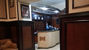 A lobby with a reception desk, leather seating, and a clock. - New Hotel (Cairo)