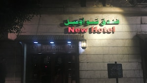 The exterior of a hotel with a sign reading "New Hotel" and another sign in a different language. - New Hotel (Cairo)