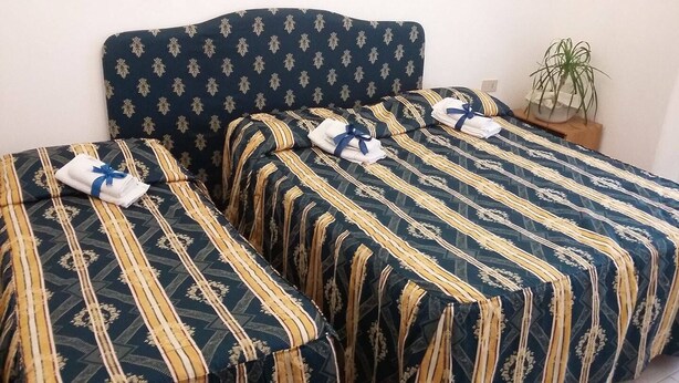 A hotel room with two beds, each with striped bedding and a matching headboard. - Hotel Ambrogini (Montecatini Terme)