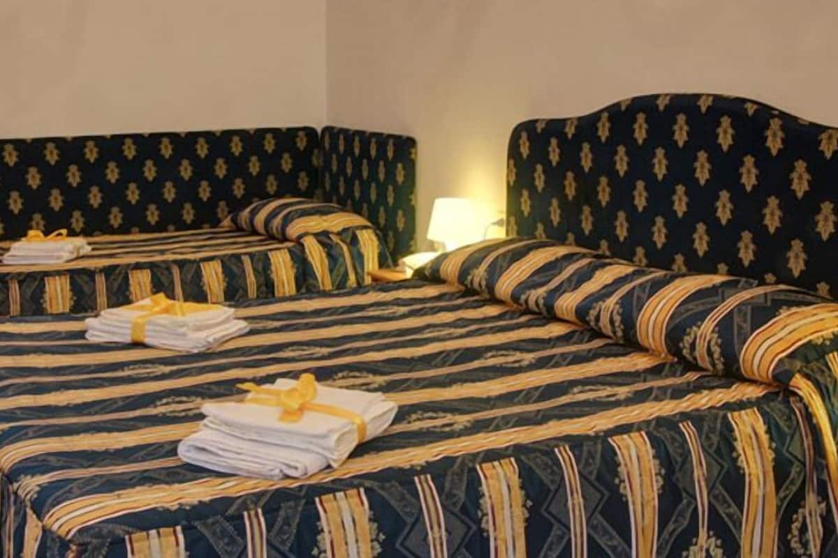 Une chambre d’hôtel avec deux lits, chacun équipé de draps et de serviettes à rayures.