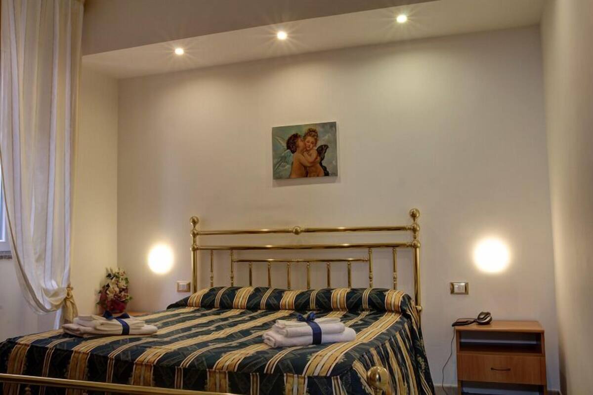 Une chambre à coucher avec un lit, une table de chevet, une lampe et un tableau au mur.