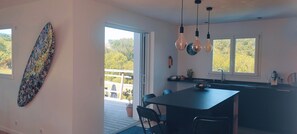 A modern kitchen with a large island, pendant lights, and a view of the outdoors.