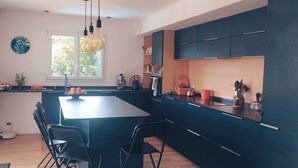 A modern kitchen with dark cabinetry, a central island, and pendant lighting. - Top villa for families: pool, games, aperitifs, beaches and mountains nearby! (Villefranque)