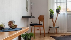 A modern living room with a wooden floor, a black chair, a wooden table, and two small side tables with potted plants. - Visitting Apartments - Podwale (Wroclaw)