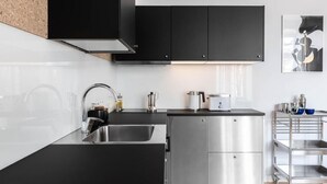 A modern kitchen with black cabinets, stainless steel appliances, and a black countertop. - Visitting Apartments - Podwale (Wroclaw)