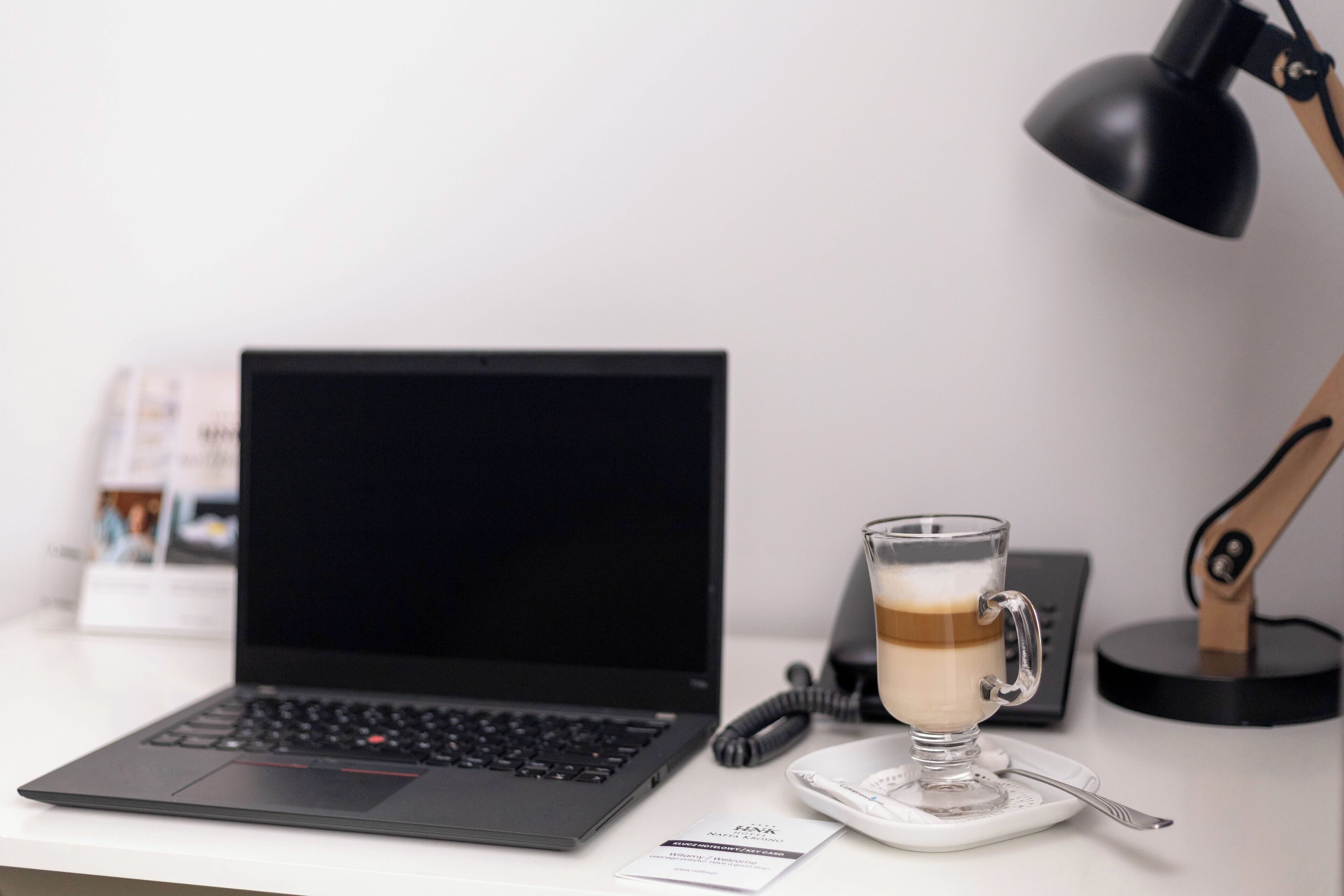 A laptop on a desk with a cup of coffee and a desk lamp.