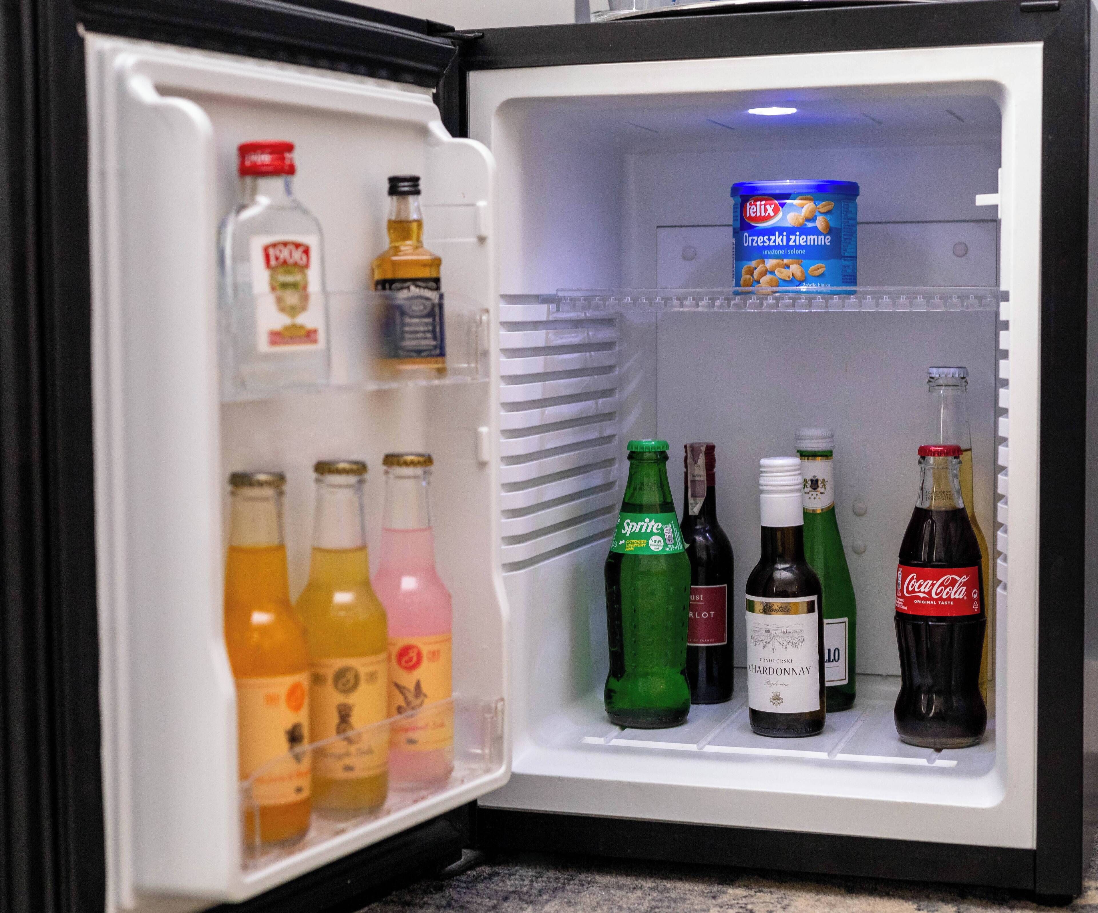 An open refrigerator containing various beverages including bottles of Sprite, Coca-Cola, and wine.