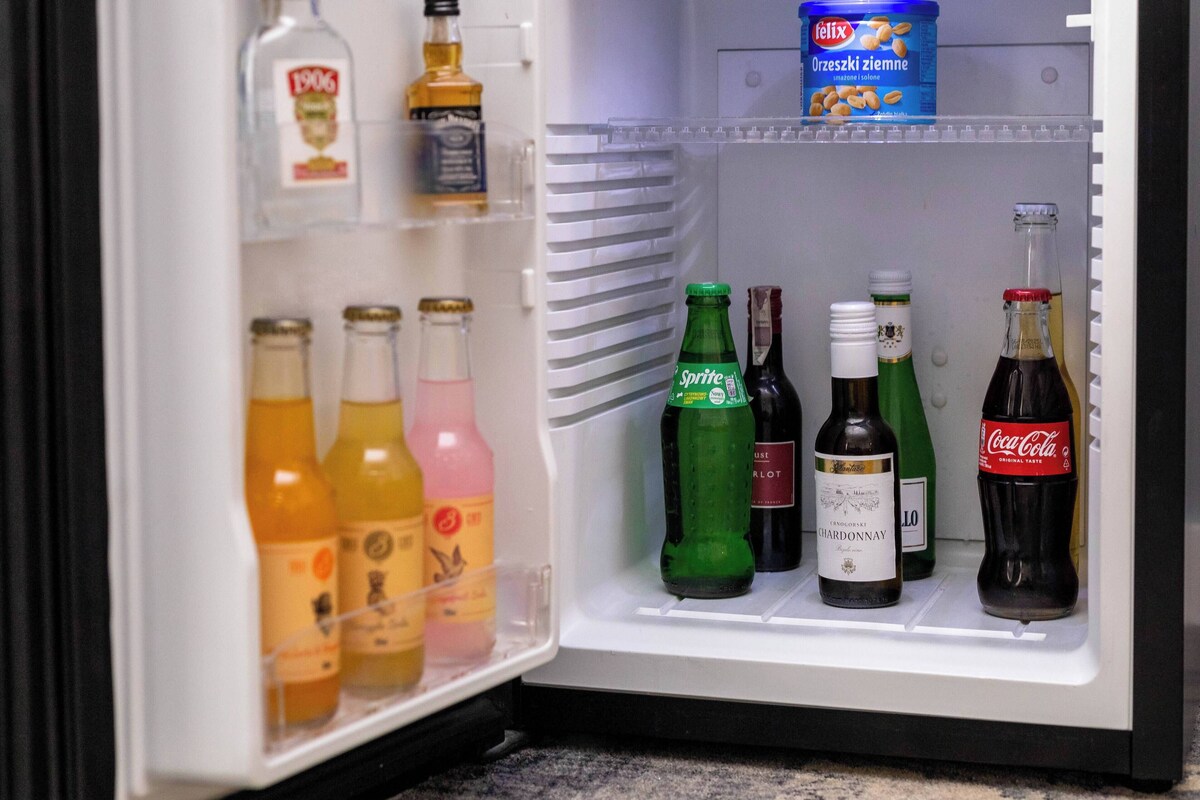 An open refrigerator containing various beverages including bottles of Sprite, Coca-Cola, and wine.