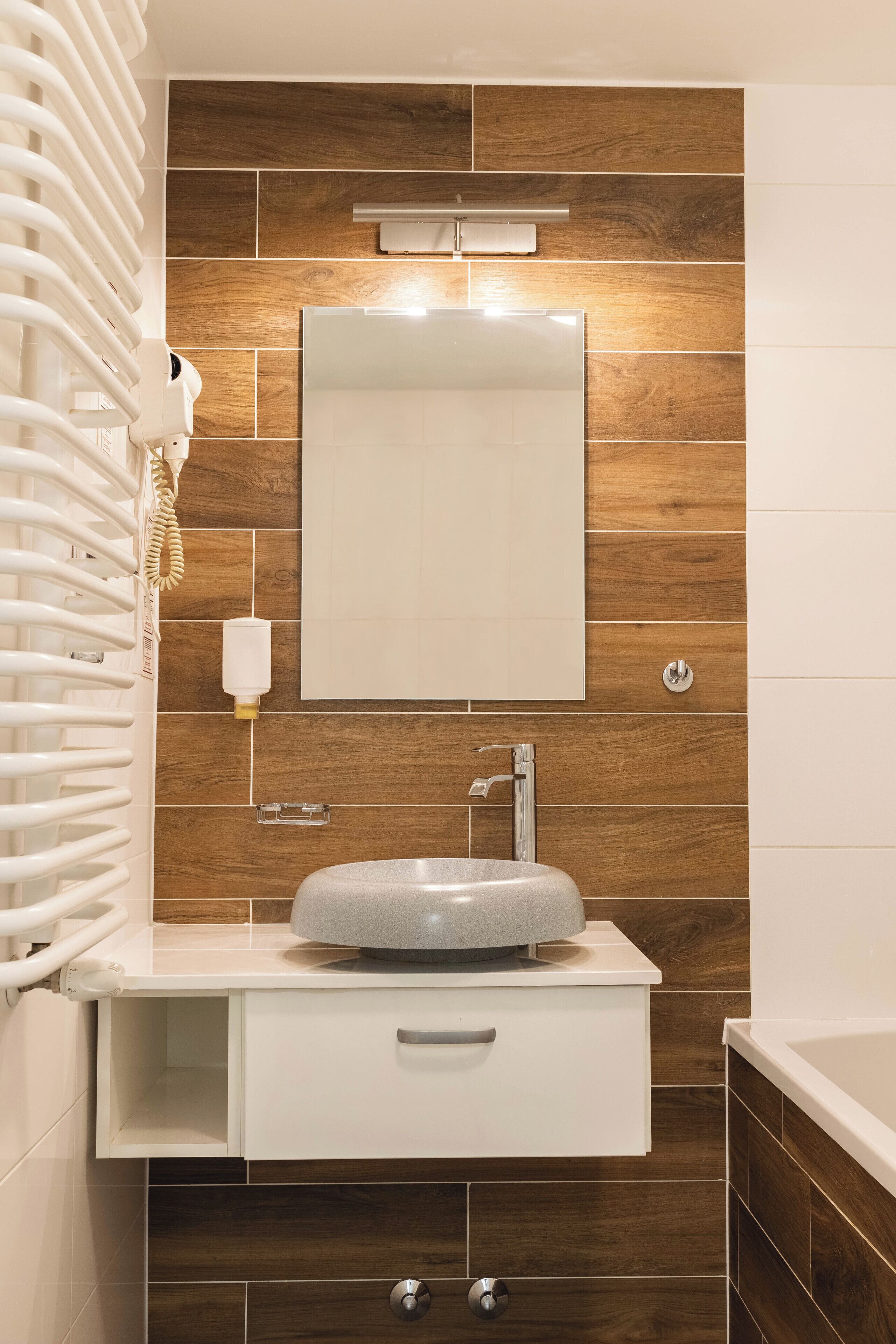 A modern bathroom with a built-in sink, a mirror, and a towel rack.