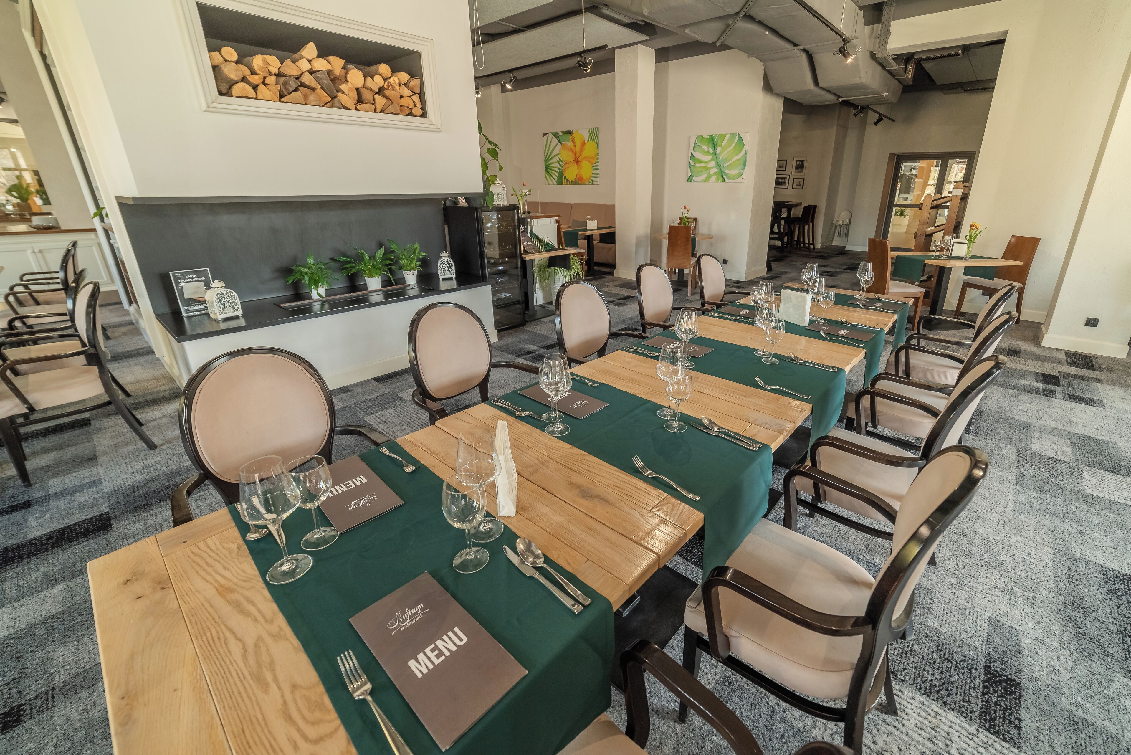 Un espace repas avec de longues tables en bois, des nappes vertes et des chaises assorties.