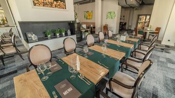 Un espace repas avec de longues tables en bois, des nappes vertes et des chaises assorties.