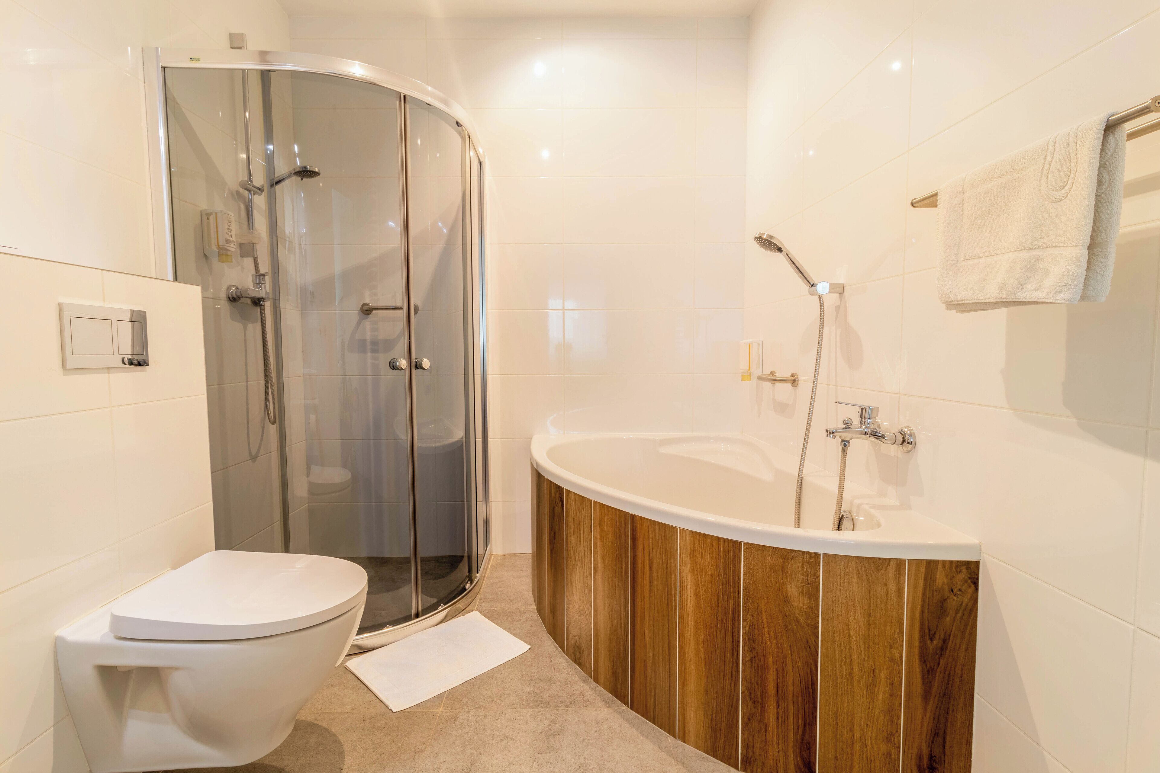 Et moderne badeværelse med en glasafskærmet brusekabine, et fristående badekar og et hvidt toilet.