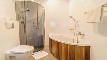 Et moderne badeværelse med en glasafskærmet brusekabine, et fristående badekar og et hvidt toilet.