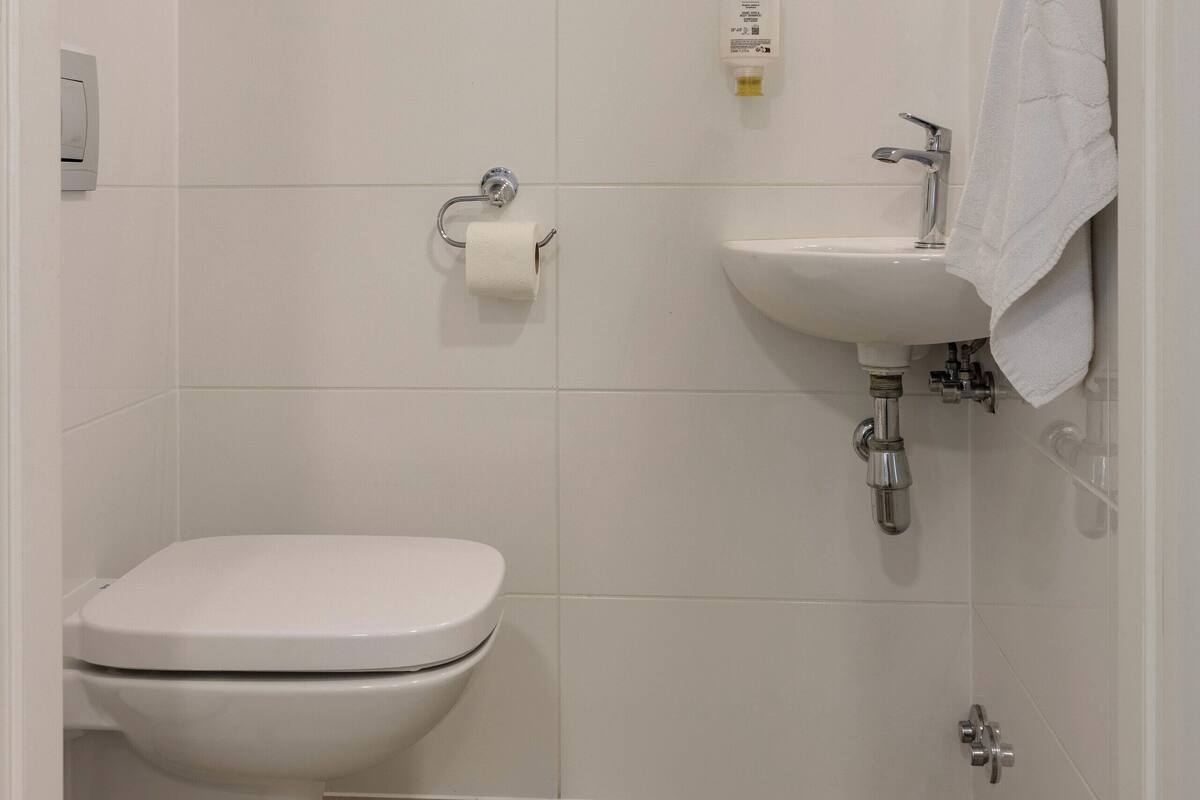 A bathroom with a toilet, sink, and mirror.