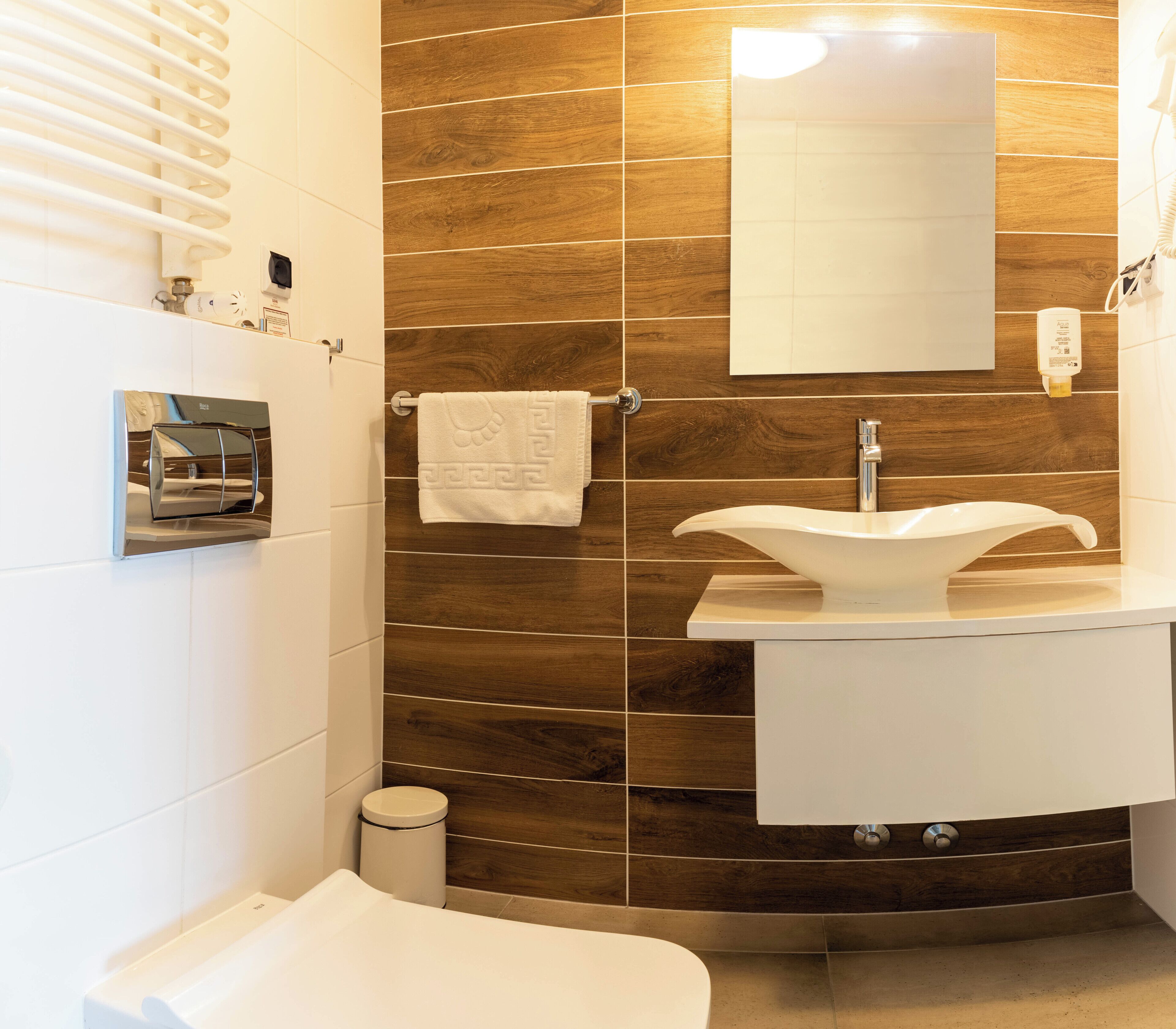 Un baño moderno con un lavamanos blanco, un espejo y un perchero para toallas.