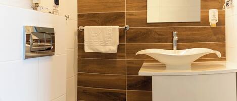 Un baño moderno con un lavamanos blanco, un espejo y un perchero para toallas.