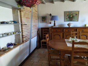 A dining area with a wooden table, chairs, a lamp, and a painting on the wall. - Country house with swimming pool (Beauville)
