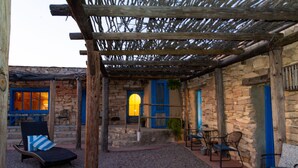 A stone building with a wooden pergola, outdoor seating, and a stone staircase.