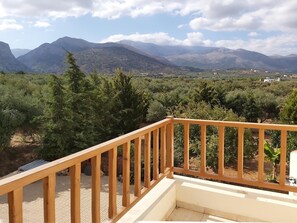 A balcony with a wooden railing overlooking a mountainous landscape with dense vegetation and scattered buildings. - Villa Armonia, Everything Is In Harmony (Agios Nikolaos)