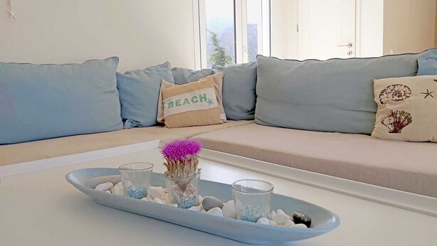 Un salon moderne avec un ensemble de canapés, un plateau contenant des objets décoratifs et une fenêtre donnant sur un beau paysage.