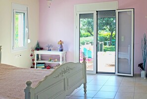 A bedroom with a bed, a white dresser, a window, and a sliding glass door leading to a balcony. - Villa Armonia, Everything Is In Harmony (Agios Nikolaos)
