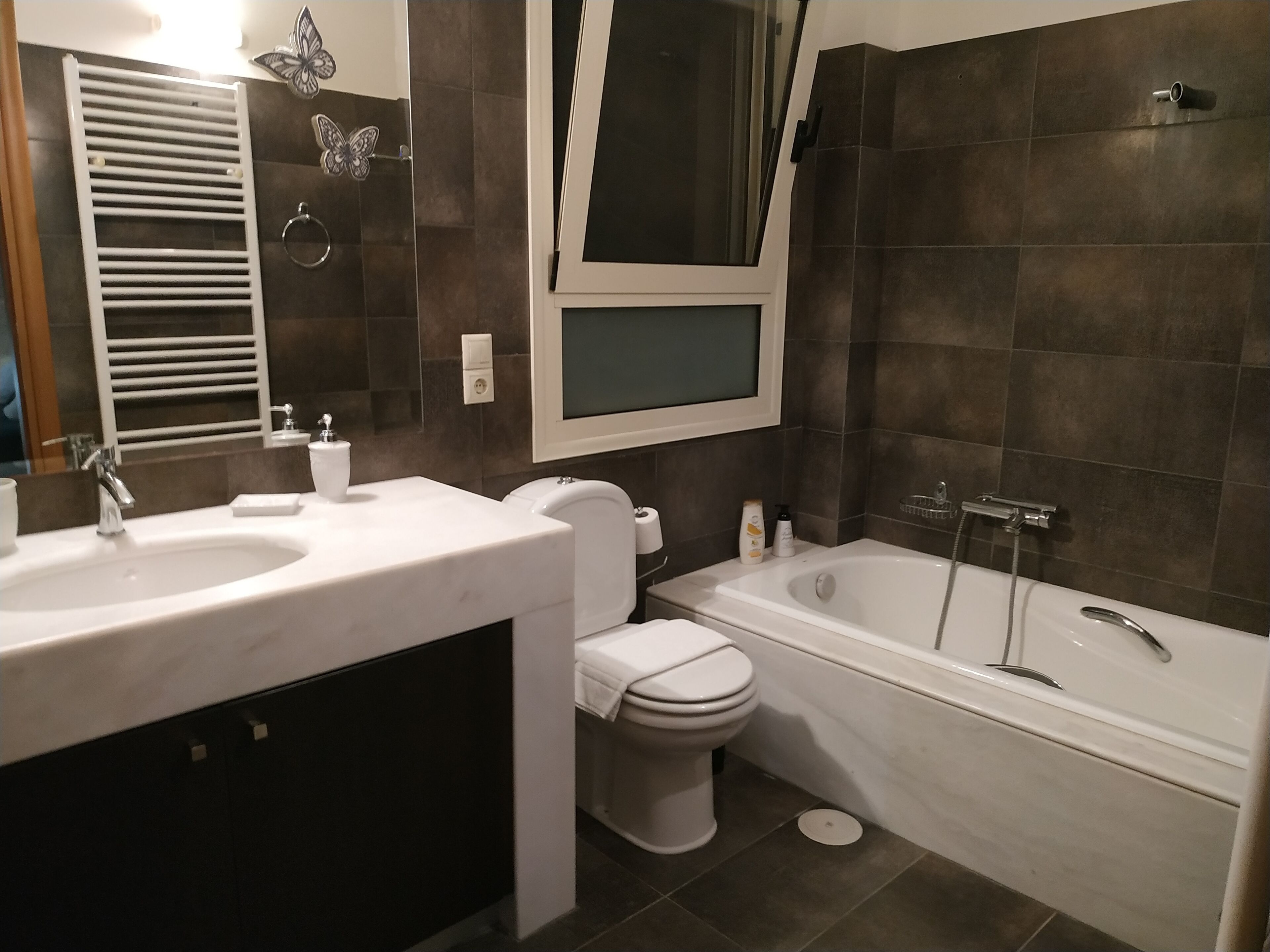 Een moderne badkamer met een wastafelmeubel met dubbele wastafel, toilet en bad.