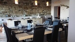 A dining area with a stone wall background, wooden tables, and black chairs. - Red House/casa Rossa - Near Civita Di Bagnoregio (Bagnoregio)