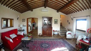 A spacious living room with a red sofa, a patterned rug, and a wooden cabinet. - Red House/casa Rossa - Near Civita Di Bagnoregio (Bagnoregio)