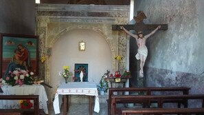 An interior of a church with a crucifix, a statue of Jesus, and a painting of the Virgin Mary.