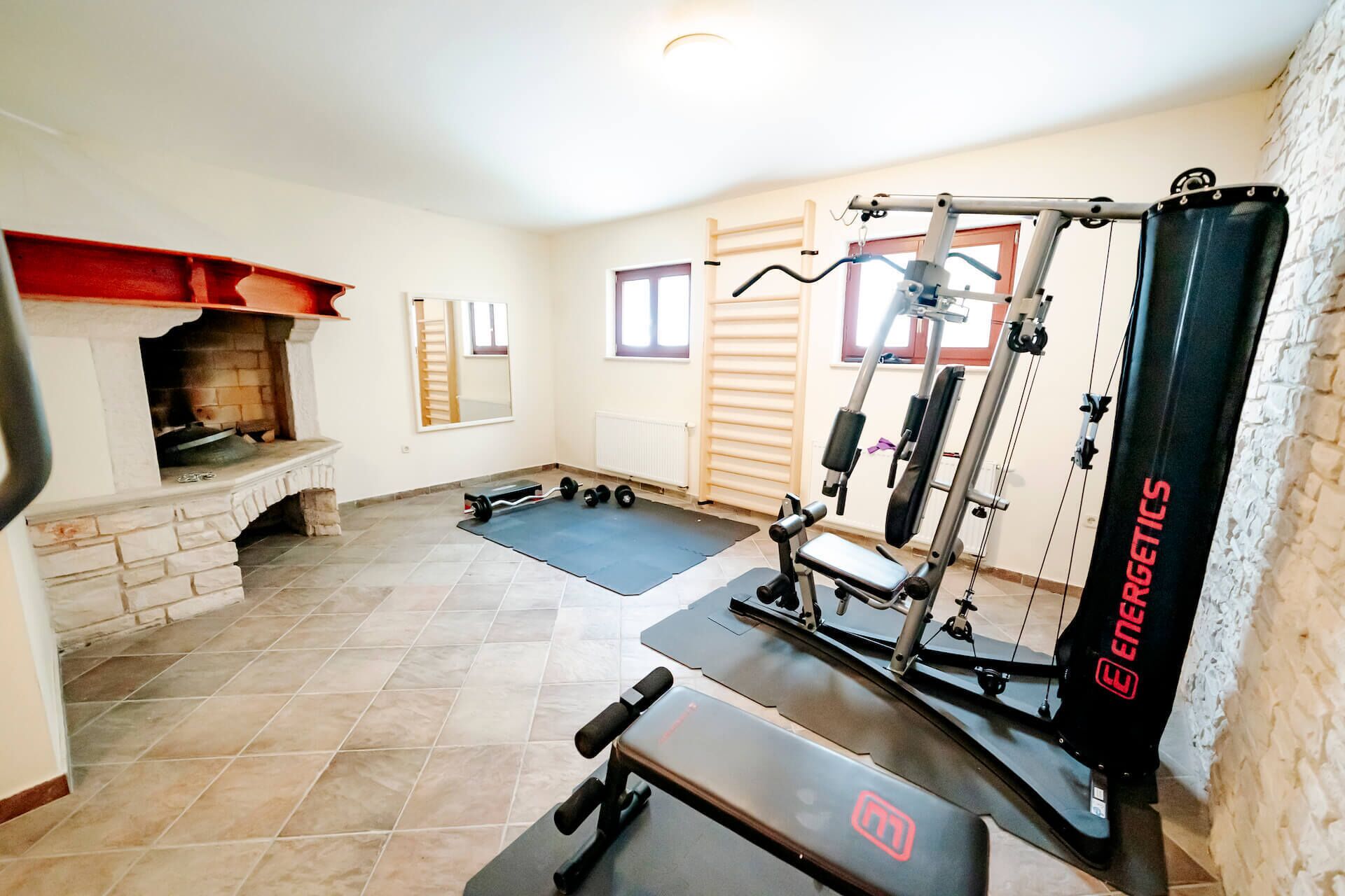 A home gym with exercise equipment, a fireplace, and a mirror.