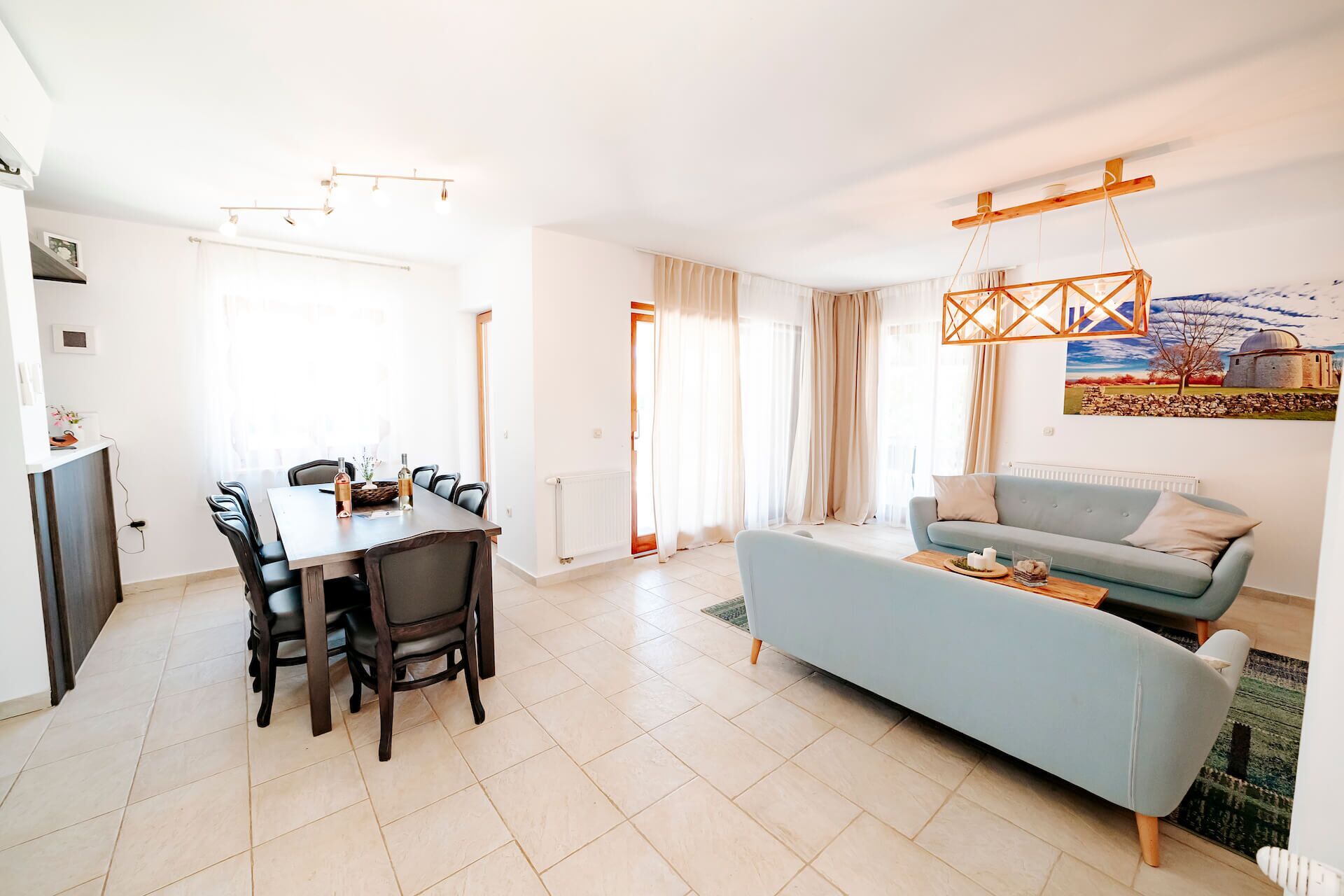 A modern living room with a dining area, light blue sofa, and a dining table with chairs.